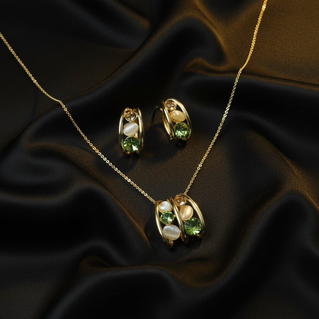 SVORA gold-tone necklace and earrings set with green crystal and cream cabochon stones in a caged design.