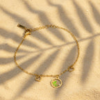 SVORA gold chain bracelet with green leaf charm, two small hearts, and a cubic zirconia stone. Adjustable.
