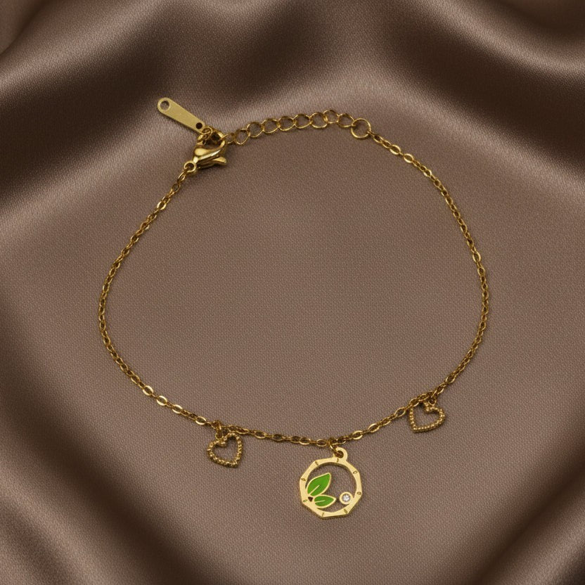 SVORA gold chain bracelet with green leaf, heart charms, and cubic zirconia stone. Adjustable.