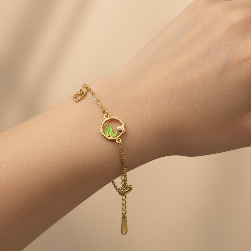 SVORA gold chain bracelet with green leaf charm and cubic zirconia accent. Adjustable, lobster clasp.