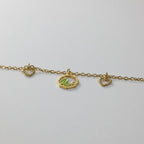 SVORA gold chain bracelet with green leaf charm, two heart charms, and a small cubic zirconia stone.