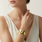 SVORA wide hammered gold cuff bracelet with a molten metal finish, made of 18K gold plated stainless steel.