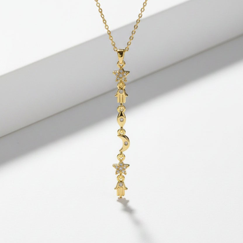 SVORA gold plated stainless steel necklace with a vertical drop of hamsa, star, moon, and eye charms.