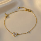 SVORA gold-plated stainless steel bracelet with a pavé CZ heart charm and a round stone accent. Adjustable.