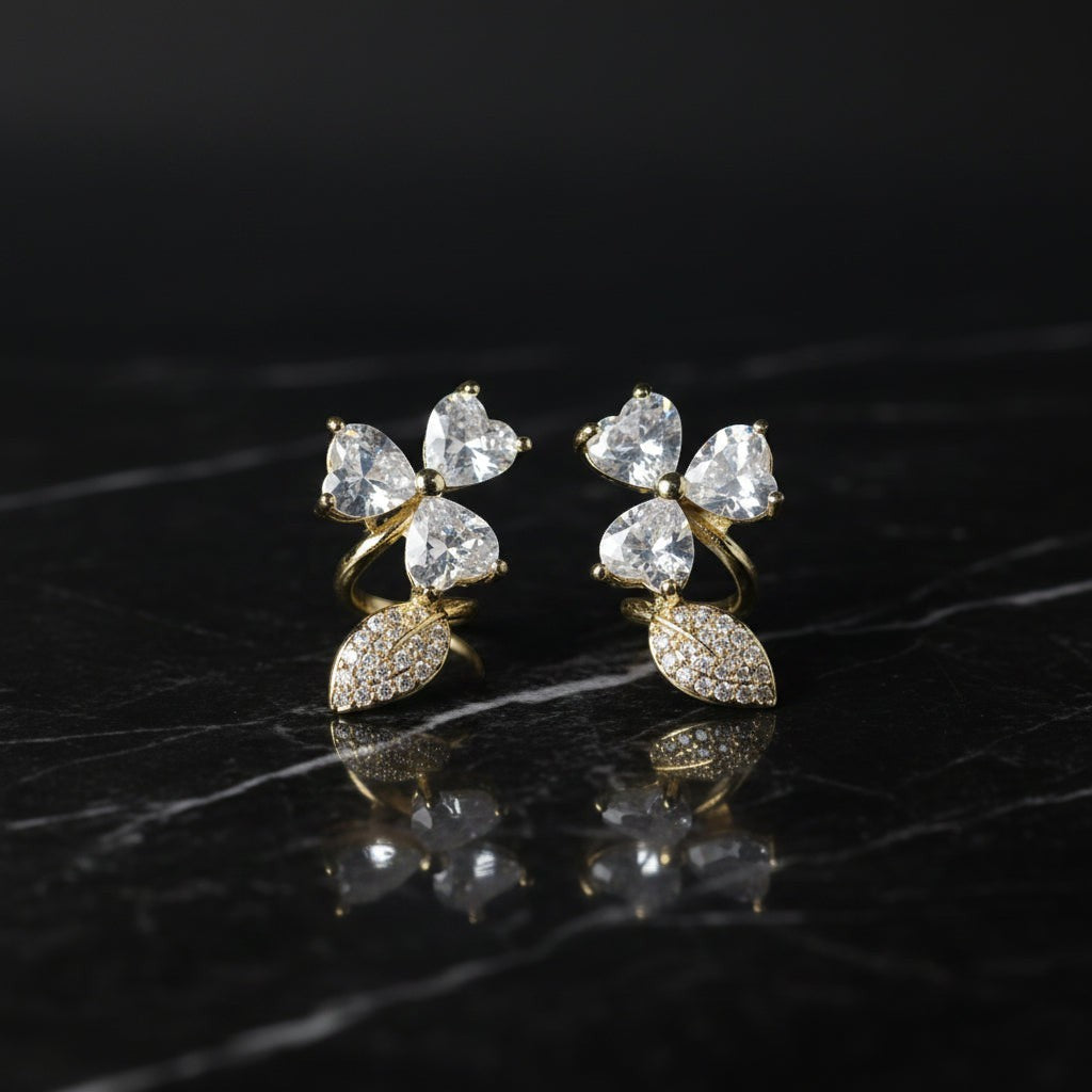 SVORA gold tone stud earrings with pavé heart petals and leaf accents, adorned with cubic zirconia.