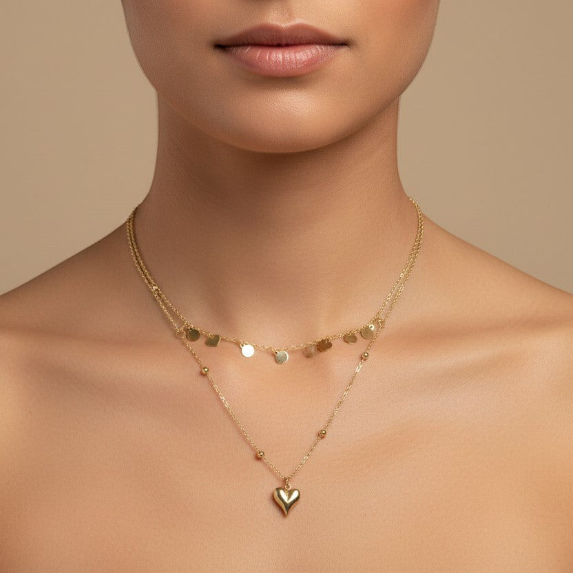 SVORA gold stainless steel layered necklace with puffed heart pendant and disc charms.