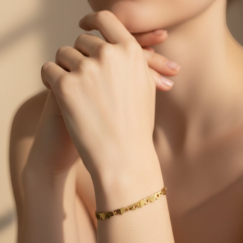 SVORA gold plated stainless steel bracelet with a delicate chain of small linked hearts. Adjustable with lobster clasp.