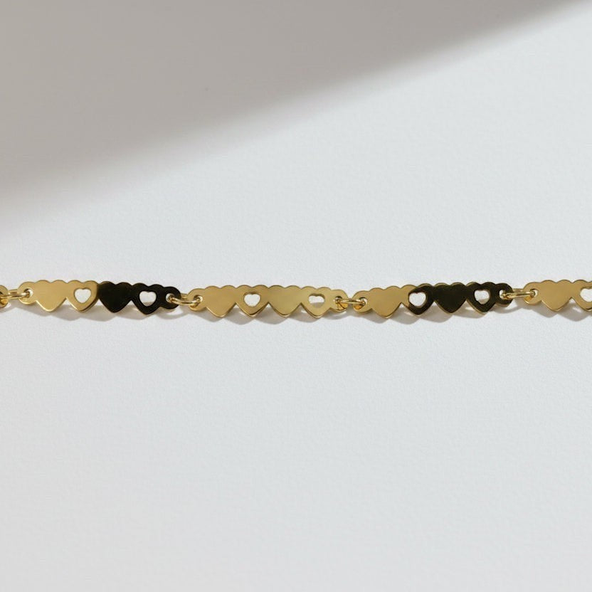 SVORA gold-plated stainless steel bracelet with a delicate chain of small, linked hearts. Adjustable with lobster clasp.