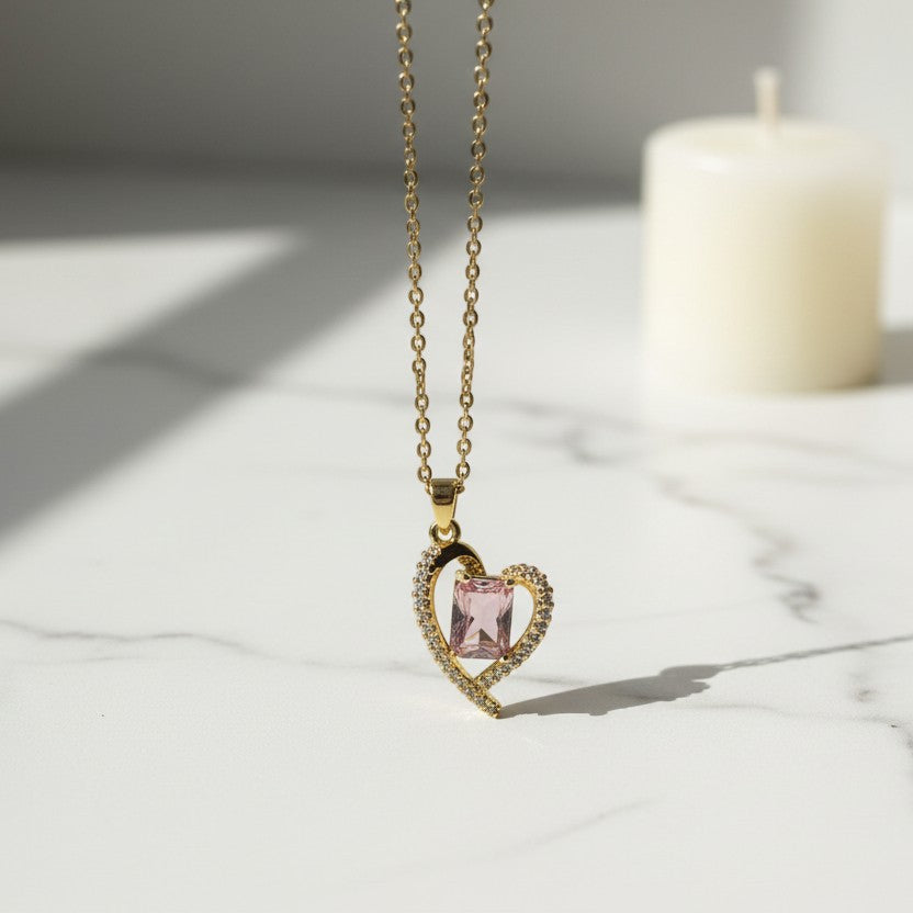SVORA gold heart necklace with a pink rectangular stone and clear accent stones. Stainless steel, 18k gold plated.