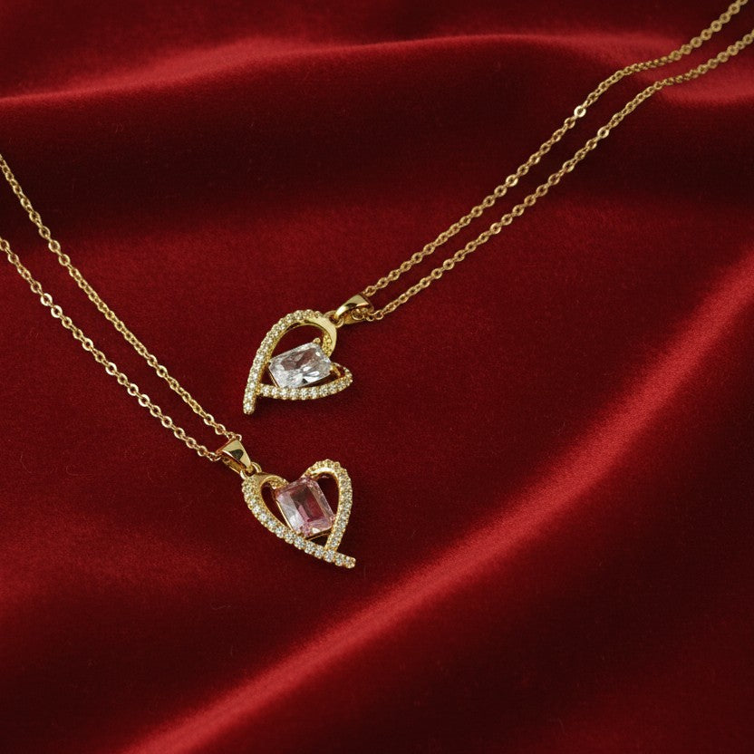 SVORA gold heart necklace with pink and clear cubic zirconia stones on a red satin background.