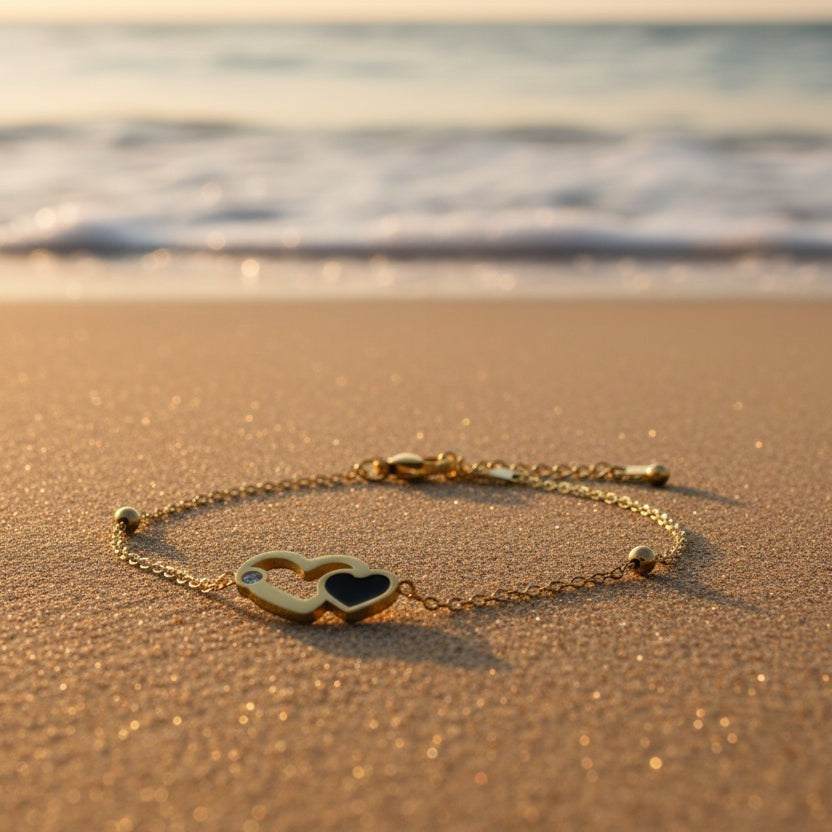SVORA gold plated stainless steel bracelet with interlocking hearts, one black enamel, one with a CZ stone.