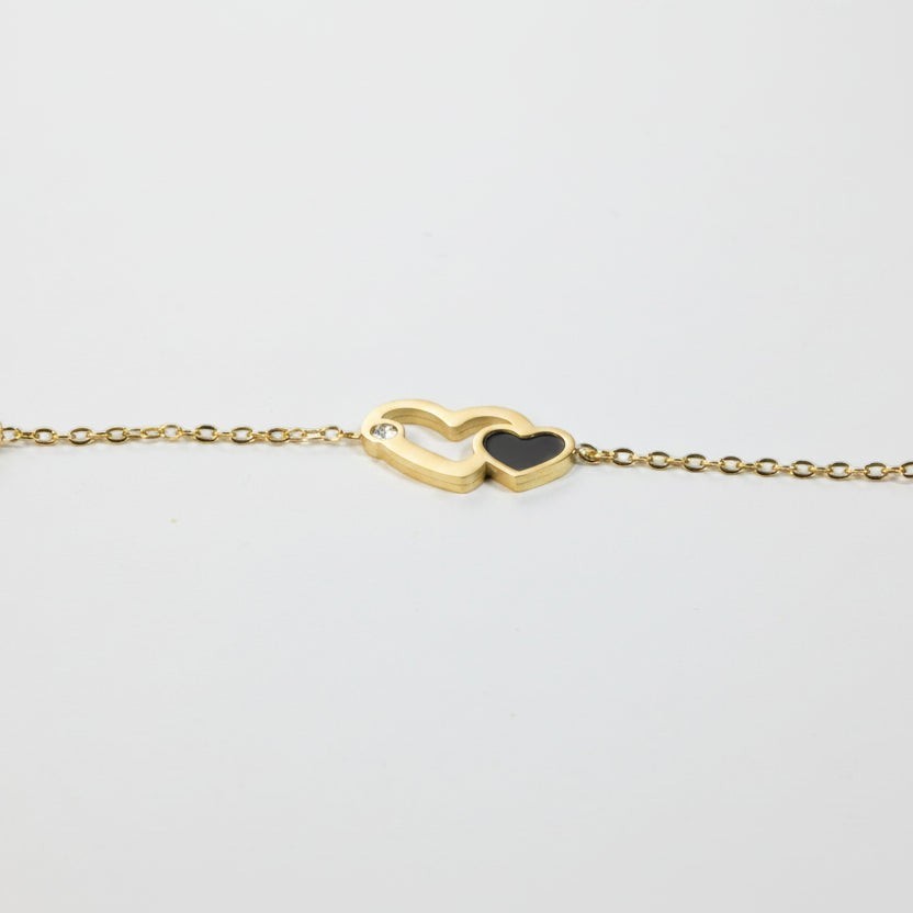 SVORA gold plated stainless steel bracelet with interlocking hearts, one black, one with a CZ stone.