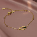 SVORA gold chain bracelet with interlocking hearts, one black and one outlined with a CZ stone.