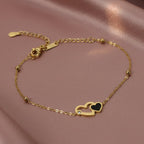 SVORA gold chain bracelet with interlocking hearts, one black and one outlined with a CZ stone.
