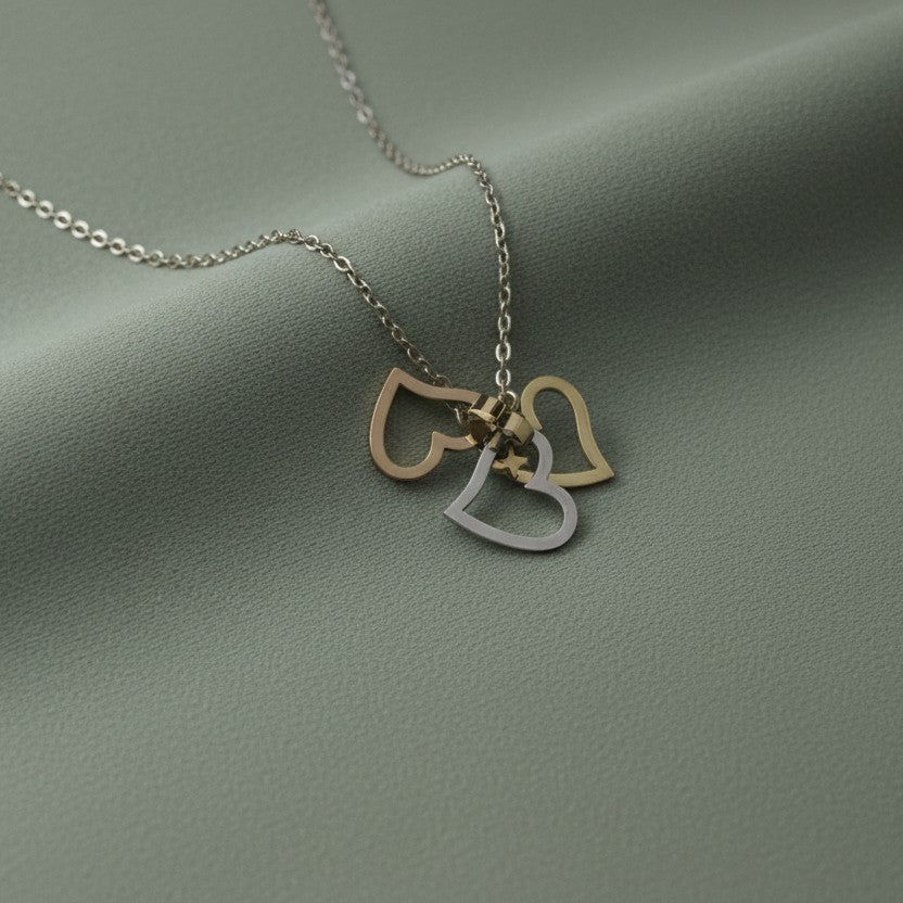 SVORA interlocking triple heart necklace with gold and silver charms on a delicate chain, symbolizing love and connection.