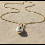 SVORA gold chain necklace with a baroque pearl pendant featuring a small amethyst-purple enamel rose and green leaves.