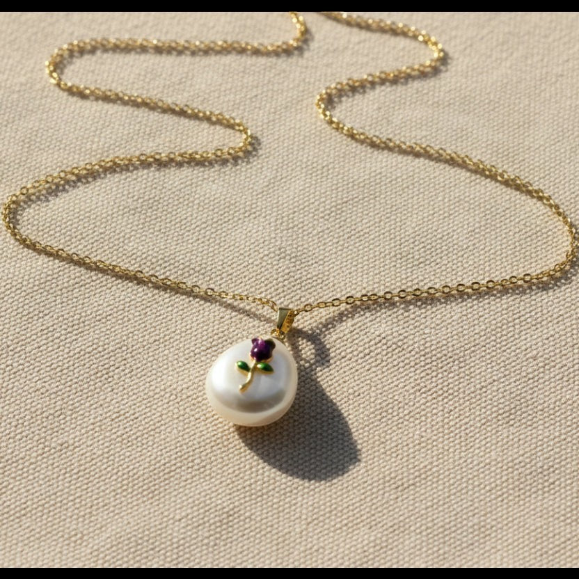 SVORA gold chain necklace with a baroque pearl pendant featuring a small amethyst-purple enamel rose and green leaves.