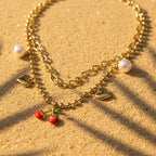 SVORA gold layered necklace with paperclip and ball-bead chains, featuring pearl, heart charms, and a cherry pendant.