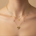 SVORA layered gold necklace with bow, heart, and solitaire charms. 18k gold-plated stainless steel.
