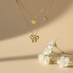 SVORA layered gold necklace with bow, heart, and solitaire charms. 18k gold-plated stainless steel.