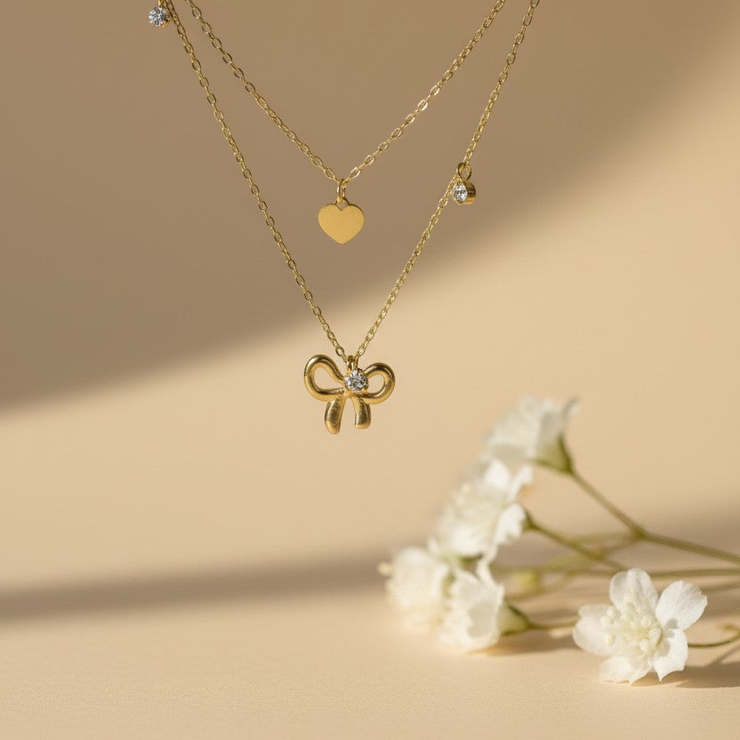 SVORA layered gold necklace with bow, heart, and solitaire charms. 18k gold-plated stainless steel.