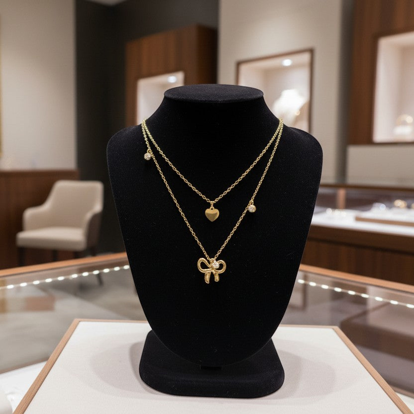 SVORA layered gold necklace with bow, heart, and solitaire charms. 18K gold-plated stainless steel.