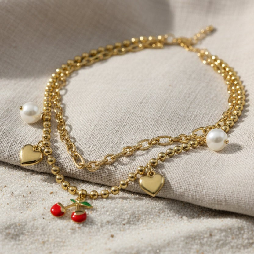 SVORA gold layered necklace with paperclip and ball-bead chains, featuring pearl, heart, and cherry charms.