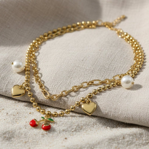 SVORA gold layered necklace with paperclip and ball-bead chains, featuring pearl, heart, and cherry charms.