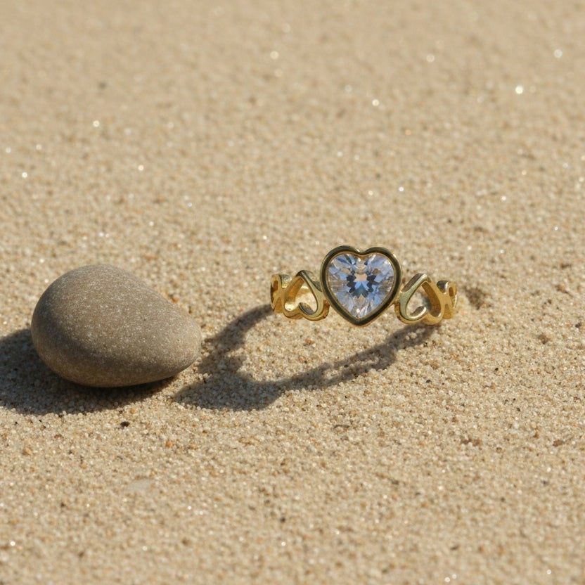 SVORA Lumiere Amour Heart Ring with a clear heart-cut stone, 18K gold plated stainless steel band with heart details.