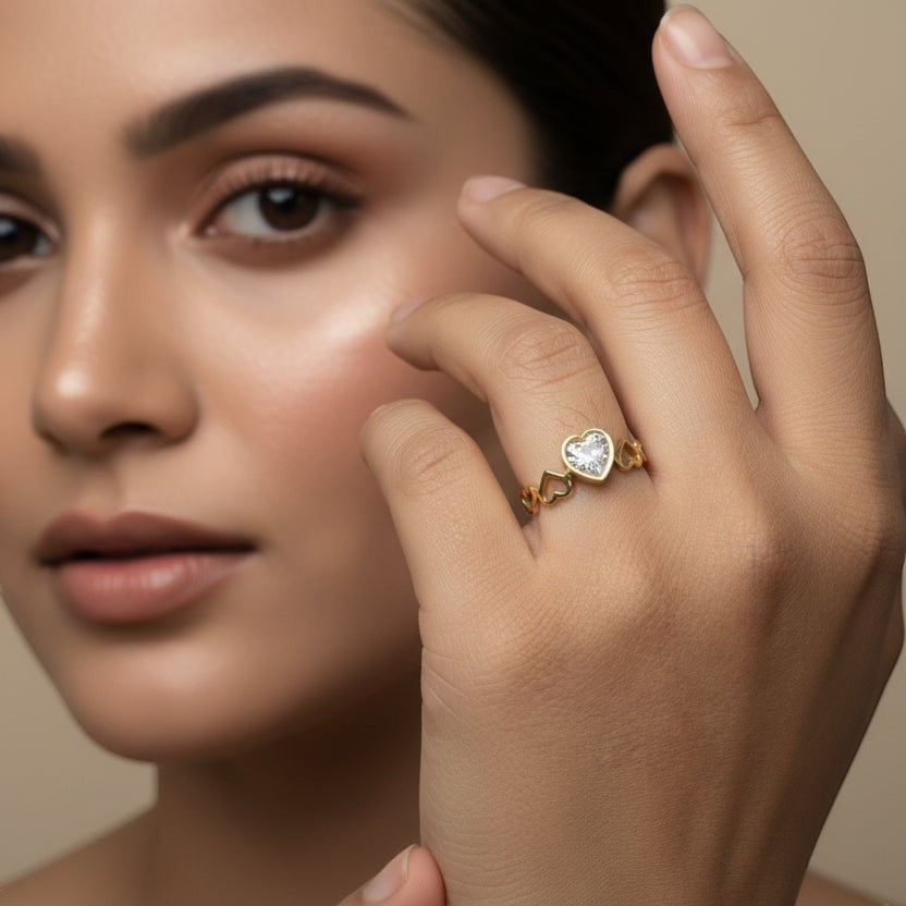 SVORA Lumiere Amour gold heart ring with a bezel-set crystal heart and open heart details on the band.