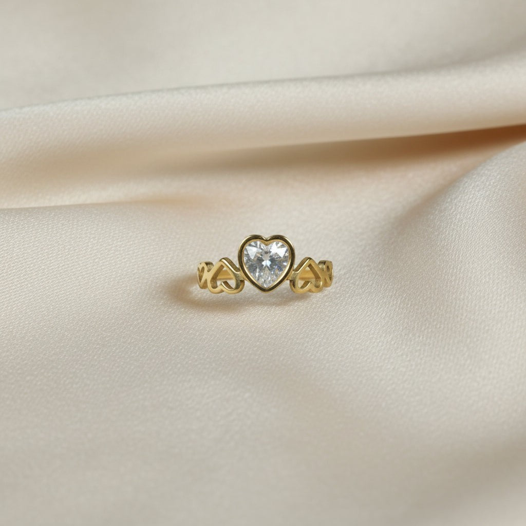 SVORA Lumiere Amour gold heart ring with a bezel-set heart-cut stone and open heart details on the band.