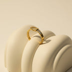 SVORA gold tone stainless steel ring with channel-set cubic zirconia stones, designed like a belt buckle.