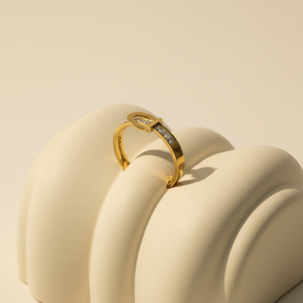 SVORA gold tone stainless steel ring with channel-set cubic zirconia stones, designed like a belt buckle.