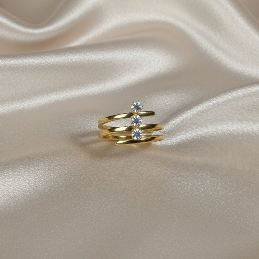 SVORA Lumiere Trilogy Spiral Ring in gold-tone stainless steel with three clear cubic zirconia stones.