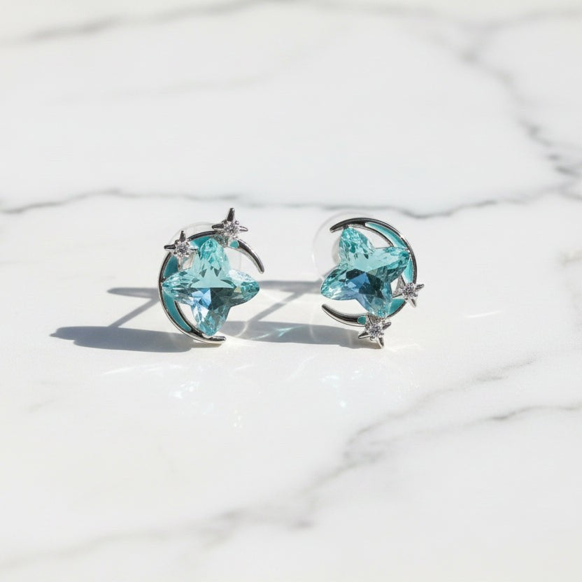 SVORA aqua cushion-cut crystal stud earrings with silver-tone crescent moon and pavé stars.