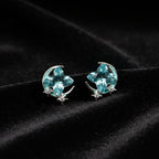 SVORA Moon Aqua Stud Earrings with cushion-cut aqua crystals, crescent moons, and pavé stars. Silver-tone.