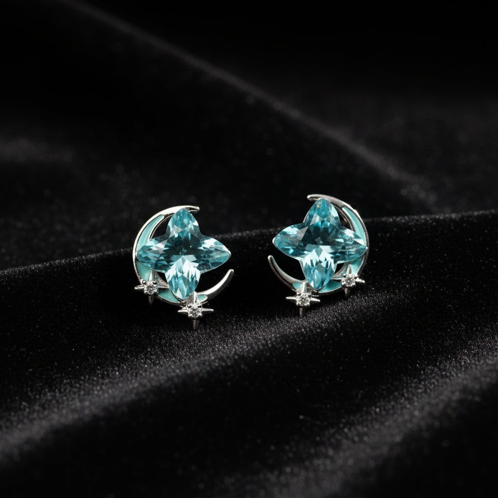 SVORA Moon Aqua Stud Earrings with cushion-cut aqua crystals, crescent moons, and pavé stars. Silver-tone.