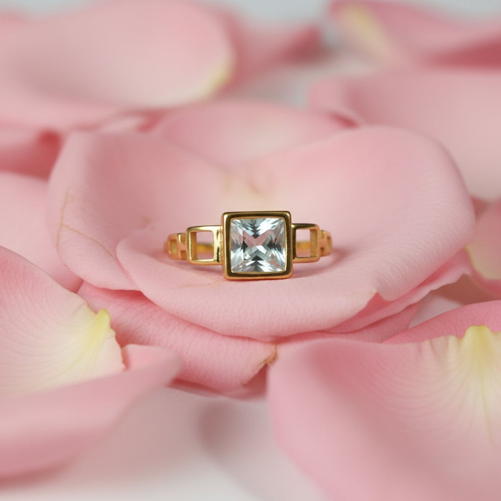 SVORA gold ring with a square-cut aquamarine stone and open square links. 18K gold plated stainless steel.