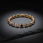 SVORA multicolour round tennis bracelet with halo links in rose gold, featuring garnet, peridot, amethyst, and peach champagne stones.