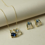 SVORA gold-tone necklace and earrings set with navy, smoky blue, and cream stones in caged design.