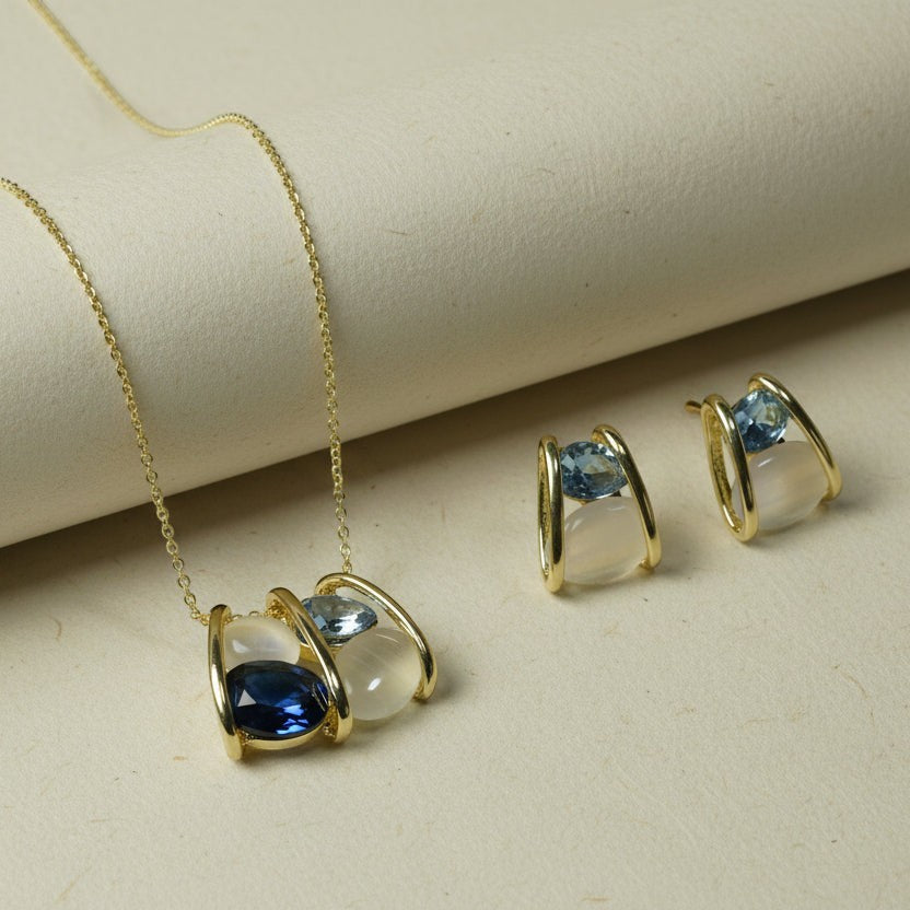 SVORA gold-tone necklace and earrings set with navy, smoky blue, and cream stones in caged design.