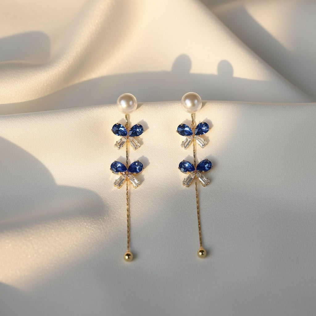 SVORA navy crystal pearl drop earrings with gold chain and baguette cubic zirconia accents.