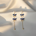 SVORA navy crystal pearl drop earrings with gold chain and baguette cubic zirconia accents.