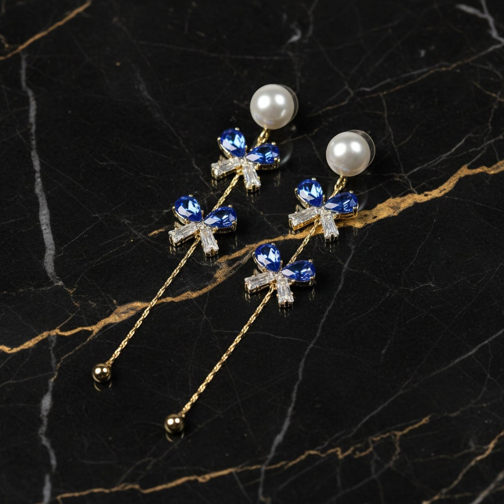 SVORA navy blue crystal bow drop earrings with pearl studs and gold chain.