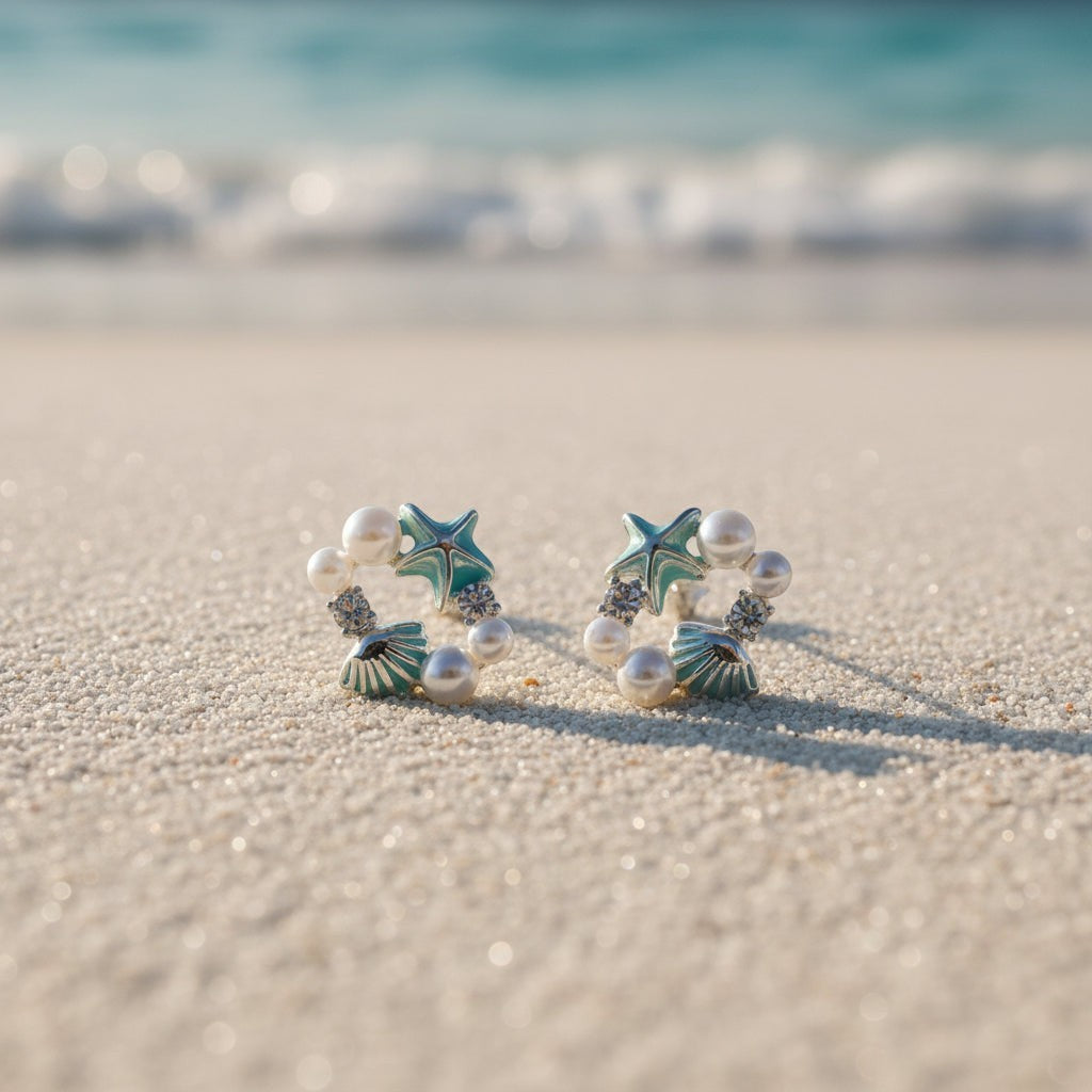 SVORA Ocean Cluster Pearl Stud Earrings with aqua starfish, shells, pearls, and crystals on a beach.
