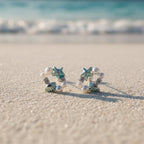 SVORA Ocean Cluster Pearl Stud Earrings with aqua starfish, shells, pearls, and crystals on a beach.