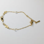 SVORA gold-plated stainless steel bracelet with pearls and black heart charms. Adjustable lobster clasp.