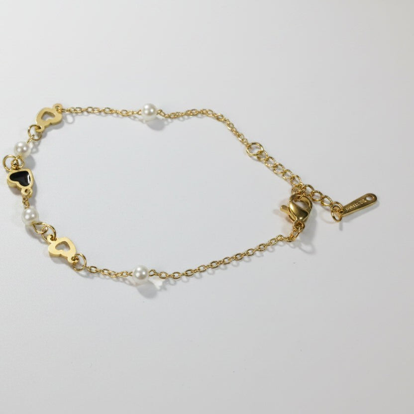 SVORA gold-plated stainless steel bracelet with pearls and black heart charms. Adjustable lobster clasp.