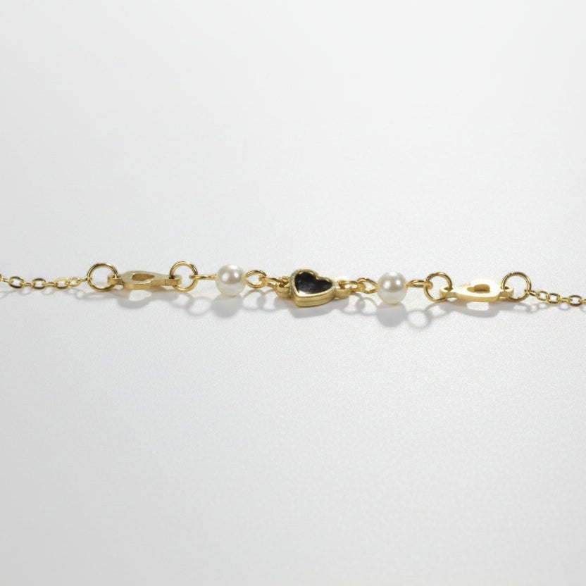 SVORA gold chain bracelet with pearls and a black heart charm. Adjustable lobster clasp closure.