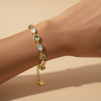 SVORA gold-tone bracelet with alternating opal grey gemstones and a good luck charm, adjustable fit.